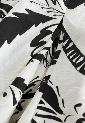 Schwarz-weißer Stoff mit auffälligen Blumen- und Blattformen. Weiche, strukturierte Oberfläche mit fallenden Falten. Leicht und leicht zerknittert im Aussehen.