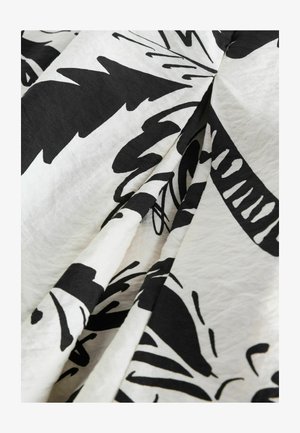 Čierno-biely materiál s výraznými kvetinovými a listovými vzormi. Mäkko textúrovaný povrch s voľnými záhybmi. Ľahký a mierne zvráskavený vzhľad.