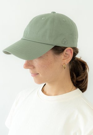 Groene katoenen baseballcap met een gestikte klep, met een klein logo op de achterkant. G gedragen met een plain wit T-shirt.