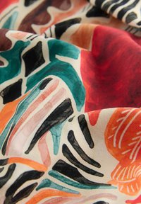 Stof med abstrakte former og penselstrøgsmønstre i grønblå, sort, rød, orange og beige toner, der viser bløde folder og tekstur.