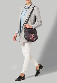 Bolso de hombro negro y gris con bordado floral y detalles circulares rojos. Incluye un bolsillo frontal y una correa larga ajustable.