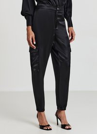 Pantaloni cargo neri in satin con vita alta, polsini elasticizzati e tasche laterali, caratterizzati da una texture liscia e una vestibilità su misura.