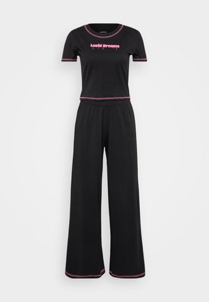 Schwarzes zwei-teiliges Loungewear-Set mit einem kurzärmligen Top mit rosafarbenem Schriftzug und weit geschnittenen Hosen mit rosa Akzenten an den Säumen. Weicher Stoff.