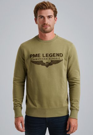 Olive green sweatshirt with round neck, long sleeves, and ribbed cuffs. Front features black embroidered text and winged logo. Soft texture.