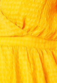 Vestido amarelo com padrão checkered texturizado, com um design plissado e tecido suave. Os detalhes incluem um corpete ajustado e uma saia em camadas.