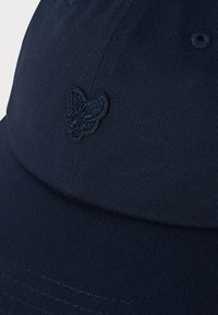 Dark blue baseball cap with a small embroidered butterfly logo on the front panel and visible stitching details.