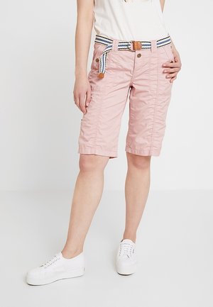 Světle růžové bermudské kraťasy s texturovaným povrchem, doplněné o vícepruhový opasek a kapsy, v kombinaci s bílými teniskami.
