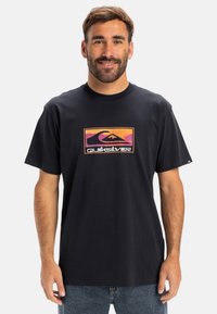Sort bomulds T-shirt med et farverigt Quiksilver-logo i et rektangulært design på fronten. Korte ærmer og en afslappet pasform.