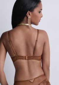 Soutien-gorge marron avec dos en dentelle, bretelles ajustables, tissu légèrement texturé et fermeture à crochet et œillet. Agrémenté de motifs floraux intricats.