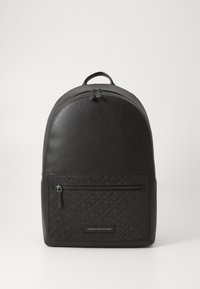 Zaino nero con corpo testurizzato e parte superiore liscia, dotato di tasca frontale con zip e dettagli del logo, che offre un design minimalista.