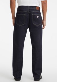 Jeans in denim blu navy visti da dietro. Le caratteristiche includono due tasche posteriori, cuciture a contrasto e un'etichetta in pelle nella vita.