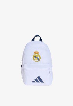 Mochila blanca con logo de Real Madrid en la parte superior y logo negro de Adidas en el bolsillo delantero, asa azul para llevar.