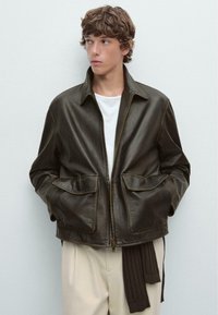 Dark brown leather jacket with a front zipper, collared neck, and two large patch pockets. Smooth texture and visible stitching details.