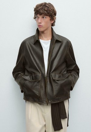Dunkelbraune Lederjacke mit einem Frontreißverschluss, Kragen und zwei großen aufgesetzten Taschen. Weiche Textur und sichtbare Nähdetails.