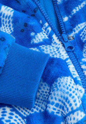 Tissu en polaire bleu avec un motif texturé ; doté d'une fermeture éclair bleue et de poignets côtelés. Matériau doux et chaud avec un design vibrant.