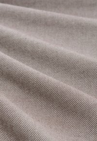 Textielstof in een zachte beige-bruin tint, met een subtiel visgraatmotief en een gladde, licht gestructureerde oppervlakte.