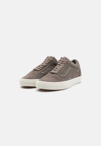 Szürke velúr sneaker fehér gumitalppal, tónusos varrással és klasszikus fűzős dizájnnal. Az oldalon egy kiemelkedő logó található.