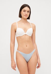 Witte gepadde bh met dunne bandjes, in combinatie met een lichtblauwe string met een merk-elastische tailleband, beide gemaakt van een soepele stof.