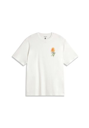 T-shirt blanc à manches courtes avec un petit graphique de fleur orange et tige verte sur le côté gauche de la poitrine, avec le texte « FAITES UN JARDIN » sous la fleur.
