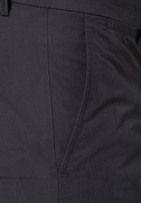 Tmavě šedé kalhoty s texturovanou látkou, předními kapsami a upravenými švy pro elegantní a moderní vzhled.