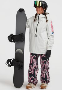Snowboard met zwarte basis en bindingen, gedragen met een witte jas en kleurrijke broek met patronen. Heeft een zigzagontwerp in roze en grijs.