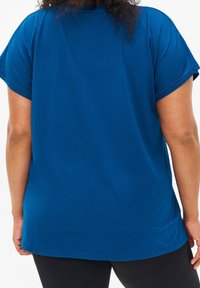 Niebieski, krótki rękaw, miękka tkanina, luźny krój i zaokrąglony dół, bez wyraźnych wzorów czy akcentów.