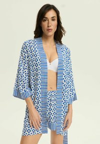 Lekki niebiesko-biały kimono z geometrycznymi wzorami i paskami; luźny krój z rękawami do 3/4 oraz pasującymi szortami pod spodem.