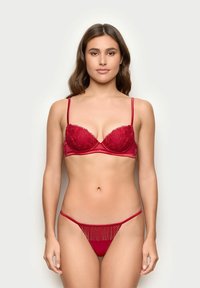Red lace and satin bra with underwire and adjustable straps, paired with a matching thong featuring fringe detailing at the front.