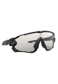 Occhiali da sole sportivi neri con design avvolgente, lenti trasparenti e accenti in gomma per una migliore presa. Presentano tempie ventilati per favorire il flusso d'aria.