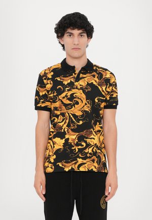 Polo noir avec un motif floral doré et marron, à manches courtes et col boutonné. Associé à un pantalon de survêtement noir.