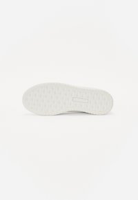 Hvit gummisåle til sneakers med et strukturert diamantmønster, avrundet form og flat bakside. Ingen synlig merking eller distinkte aksenter.