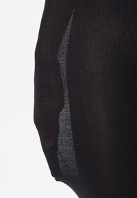 Črne prosojne nogavice z teksturiranim vzorcem in prozornim panelom ob strani, ki poudarjajo prilegajočo se in gladko zasnovo.