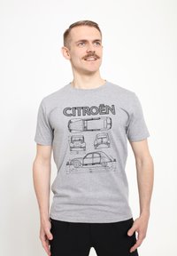 Grå bomuld T-shirt med sorte stregtegninger af Citroën-biler og ordet "CITROËN" trykt ovenover. Korte ærmer, rund hals.