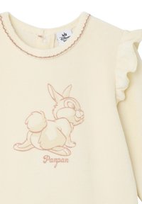 Helle gelbe Fleece-Oberteil mit Rüschenschultern, das eine pinke Illustration eines Kaninchens und den Text "Panpan" darunter zeigt.