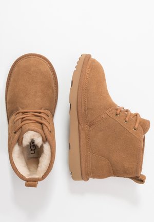 Bottines en daim marron avec semelles en caoutchouc beige, lacets sur le devant et doublure intérieure blanche et moelleuse, vues de dessus et de côté.