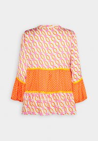 Blouse à manches longues aux motifs géométriques et à pois orange, rose et blanc, avec ourlet et poignets à volants, vue de dos.