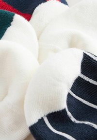 Calze bianche, blu e verdi. Presentano motivi a righe, una consistenza morbida e un design elasticizzato. Inclusi accenti di colore variabile.