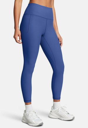 Blue ribbed leggings with a high waistband, featuring side pockets and smooth texture. Paired with white sneakers and ankle socks.