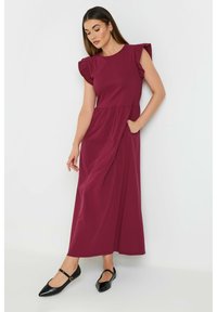 Burgundy maxi-mekko, jossa on lyhyet röyhelösoljet, tiivis yläosa, vyötärösauma ja sivutaskut. Yhdistetty mustien kärjetön kenkien kanssa.
