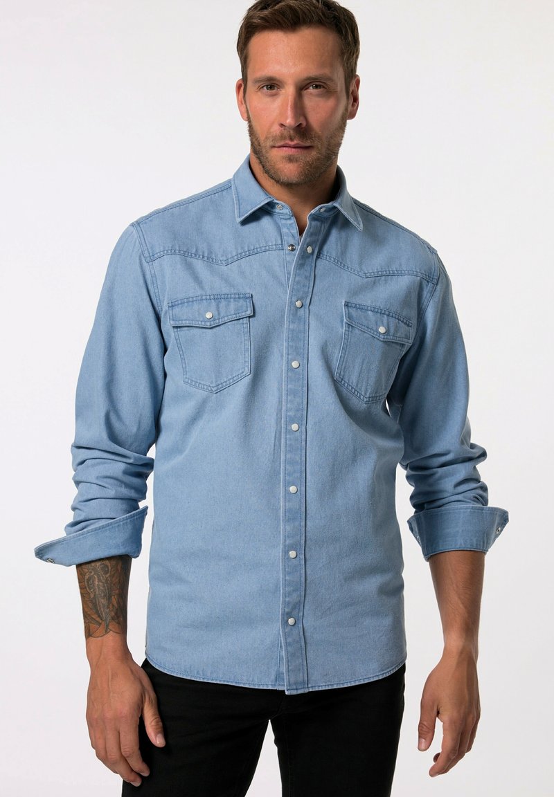 Hellblaues Denimhemd mit zwei Brusttaschen, durchgehender Knopfleiste und langen Ärmeln, die an den Bündchen hochgerollt sind. Mit Kontrastnähten.