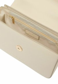 Portefeuille beige avec une texture lisse, poche zippée dorée et fermeture avec accent métallique. L'intérieur possède une doublure en tissu et un détail de marque.