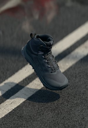Grau outdoor Stiefel mit strukturiertem Stoff, gepolstertem Knöchelschutz und einer robusten Sohle. Verfügt über Schnürsenkel und eine verstärkte Zehenkappe, schwebt über einer Straße.