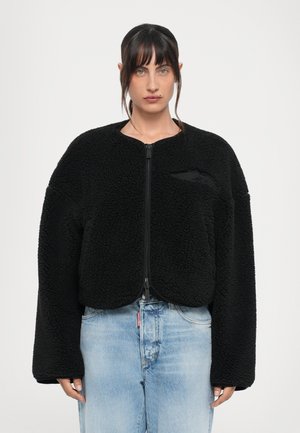 Black faux fur bomber jacket with a round neckline, zip closure, and oversized sleeves. Features a subtle textural pattern and a small logo detail.