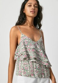 Top sin mangas con estampado floral y volantes, en colores verde, rosa y blanco. Tejido ligero con un diseño de escote en V.
