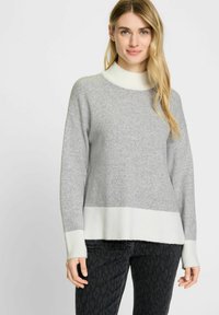 Grijze gebreide trui met een hoge witte geribbelde halslijn en een witte geribbelde zoom, met een zachte textuur en een relaxed fit.