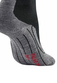 Calzino nero e grigio con texture a costine, imbottitura sul tallone e scritte rosse. Il design include un supporto arco decorato.