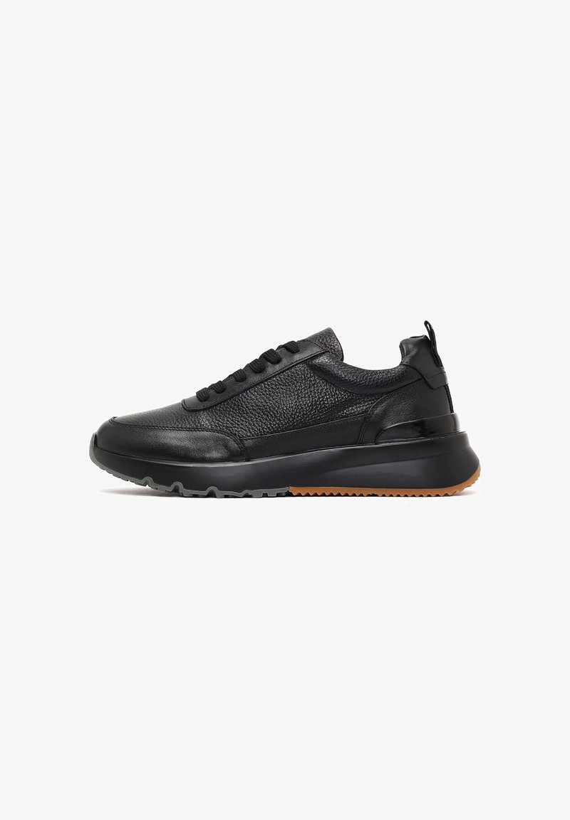Zapatillas de piel negra con paneles texturizados, seis ojales, un collar acolchado y una suela de goma con un borde de color goma en contraste.