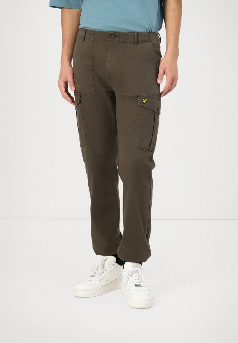 Olive zelené cargo nohavice z bavlny so slim fit, obsahujúce bočné vrecká a žltú nášivku na ľavom vrecku.