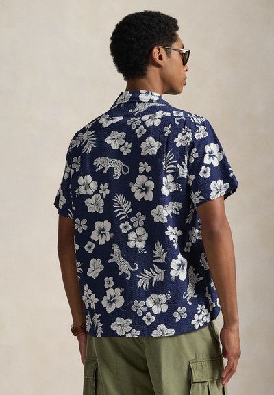 Koszula z krótkim rękawem w kolorze granatowym z białymi wzorami kwiatowymi i panterką, wykonana z teksturowanej tkaniny, z kołnierzykiem.