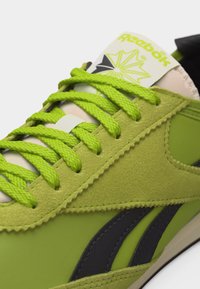 Baskets Reebok vertes avec des lacets vert citron, détails en daim et logo noir sur le côté, vues de dessus et de côté.